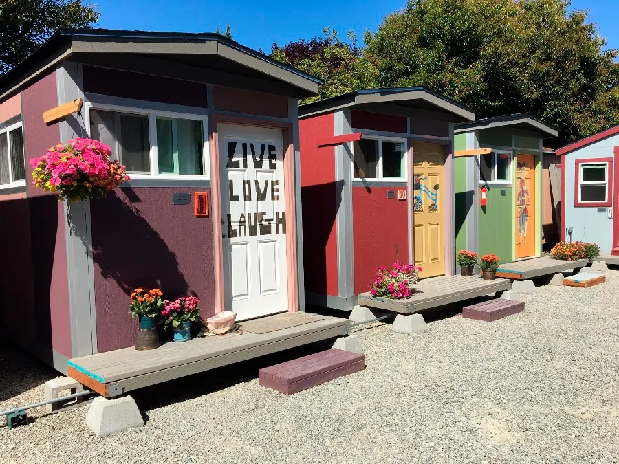 Row of small colorful tiny homes with flowers at the doors.